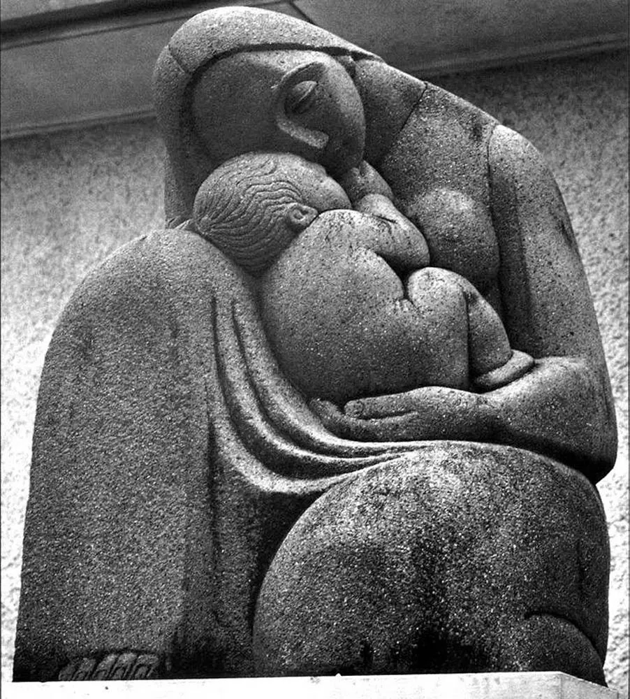 A stone sculpture of a mother tenderly cradling her child
