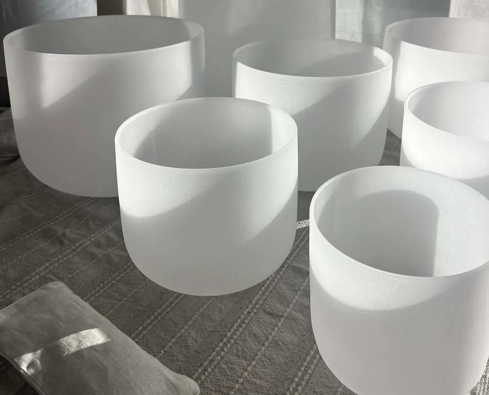 A collection of frosted crystal singing bowls arranged on linen